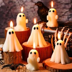 halloween candles with ghost faces on them sitting in front of an old trunk