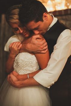 a bride and groom embracing each other in front of a fire at the end of their wedding day