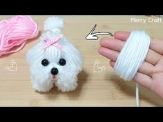 a small white dog with a pink bow on it's head next to yarn