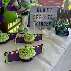 some cupcakes are sitting on a table with buzz lightyear figures in the background