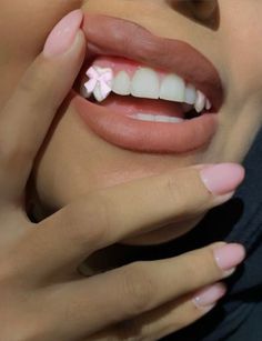 a woman with pink and white nails holding her hand up to her face while smiling