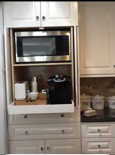 a microwave oven sitting above a counter in a kitchen with white cabinets and black counter tops