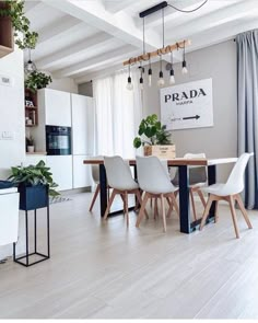 a dining room table with white chairs and plants