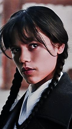 a woman with braids in her hair wearing a black jacket and white dress shirt