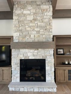 a living room with a stone fireplace and built - in entertainment center next to it