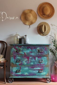 two hats are hanging on the wall above an old dresser with wheels and drawers in front of it