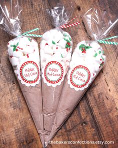 three cones filled with marshmallows on top of a wooden table next to candy canes