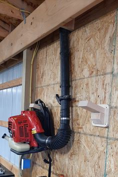 a red blow dryer sitting on top of a wooden wall next to a pipe