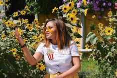 a woman with sunflowers painted on her face is standing in front of flowers