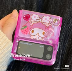 a pink hello kitty cell phone case sitting on top of someone's lap,