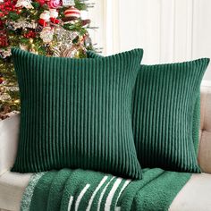 two green pillows sitting on top of a couch next to a christmas tree