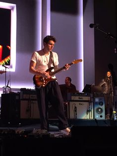 a man standing on top of a stage holding a guitar