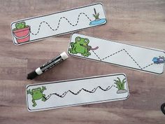 three bookmarks with pictures of frogs and plants on them, one has a pen in it