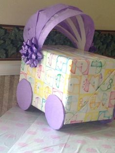 a present wrapped in paper with purple ribbon and bow on it sitting on a table