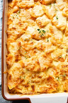 a casserole dish with cheese and herbs in it on a gray tablecloth