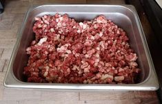 a metal pan filled with meat on top of a wooden table