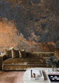 a living room with a couch, coffee table and large rock wall in the background