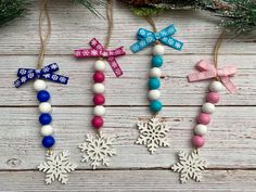 three wooden beads with bows and snowflakes hanging from them on a white wood background