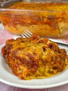 a white plate topped with lasagna next to a casserole dish