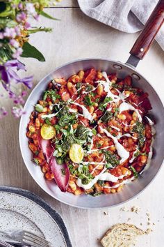 a pan filled with food next to some bread and flowers