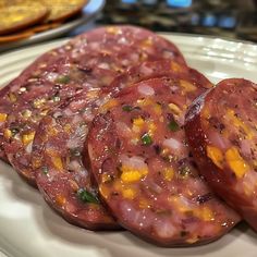 three slices of sausage on a plate with other food items in the backround