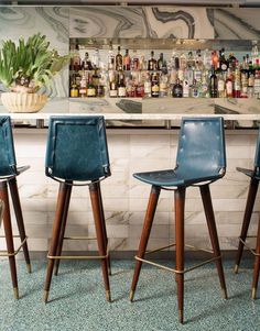 three blue bar stools sitting in front of a bar