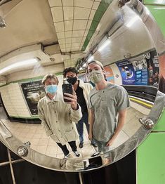 three people standing in front of a mirror taking a selfie with their cell phone