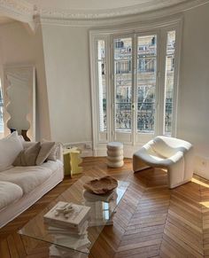 a living room filled with white furniture and lots of windows in the wall behind it