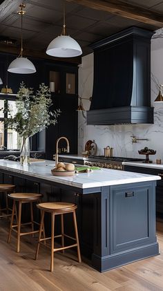 a large kitchen with black cabinets and marble counter tops, wooden stools on the floor