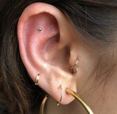 a close up of a person's ear with two gold hoops on it