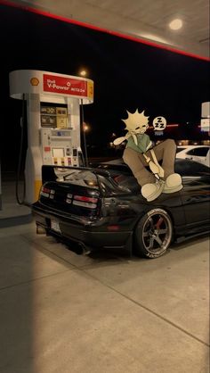 a car parked in front of a gas station with a cartoon character sitting on top of it