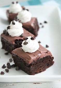 three pieces of chocolate cake on a plate with whipped cream and chocolate chips around them