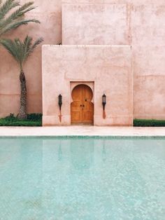 an outdoor swimming pool with a door and palm trees