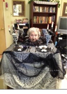 an old woman sitting at a table with halloween decorations on it