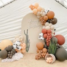 an arch made out of balloons and other items sits in front of a white tent