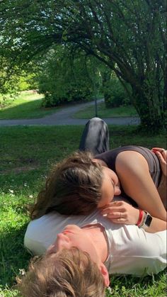 two people are laying on the ground in the grass