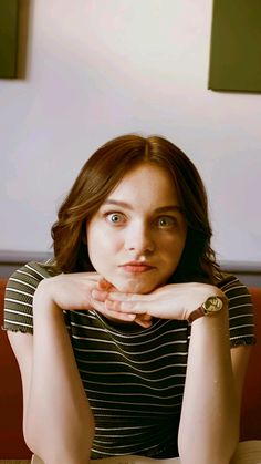 a woman sitting at a table with her hands on her chin and looking to the side