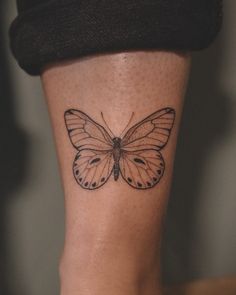 a butterfly tattoo on the leg of a woman's leg, with black and white ink