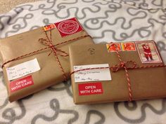 two packages wrapped in brown paper and tied with red twine on top of a bed