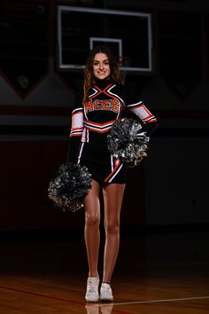 a cheerleader is walking down the court with her pom poms