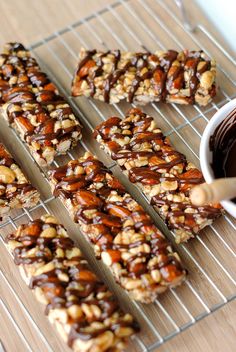 chocolate and nuts are arranged on a cooling rack next to a bowl of dipping sauce