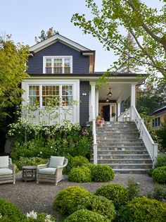 a blue house with steps leading up to the front door and sitting area on graveled patio