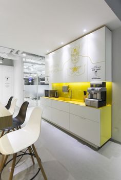 a kitchen with yellow counter tops and white chairs in front of the counter top is a coffee machine