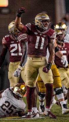 the maroon and gold football team is playing against each other on the field with their arms in the air