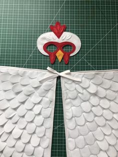 paper cut out to look like an angel with wings and a rooster mask on it