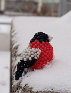 a beaded bird sitting on top of snow covered ground