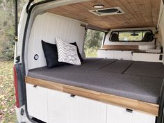 the back end of a van with a bed and pillows on it's side