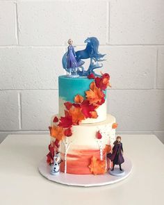 a three tiered cake decorated with leaves and figurines