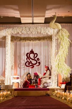 a man and woman sitting in front of a decorated stage with candles on the floor