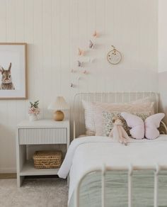 a white bed sitting next to a nightstand with two stuffed animals on top of it